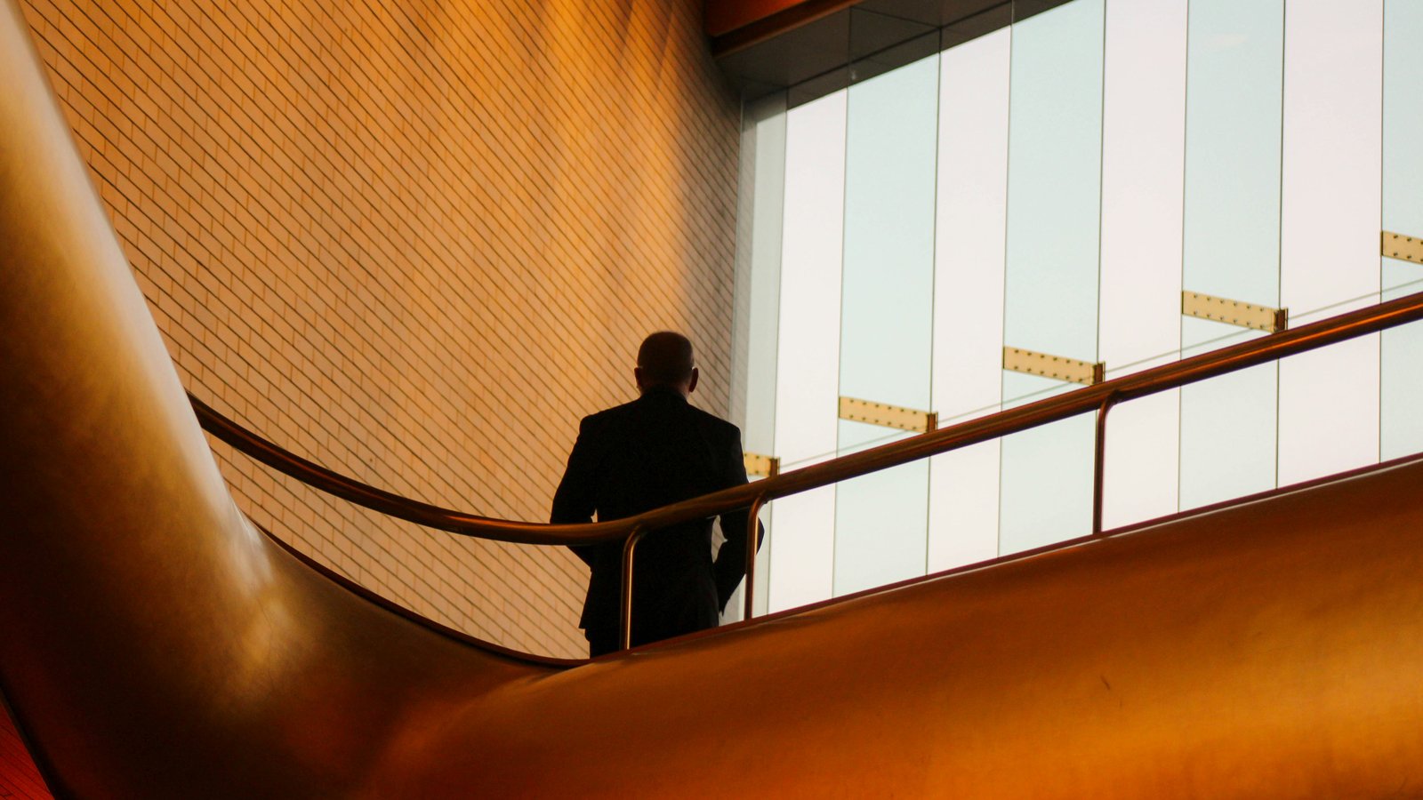 Silhouette of a businessman walking up a staircase toward a bright window